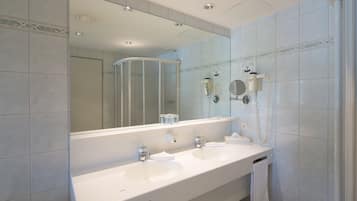 A bathroom with two sinks, a large mirror, and a shower enclosure.