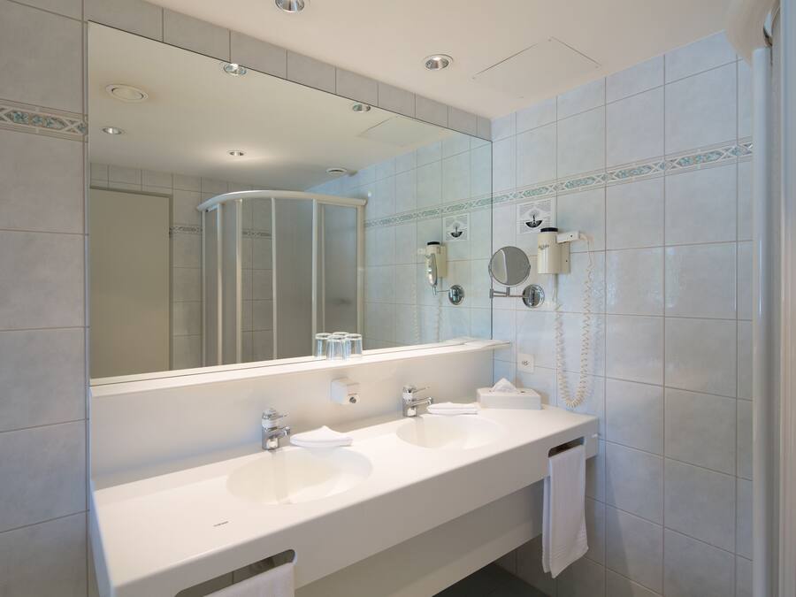 A bathroom with two sinks, a large mirror, and a shower enclosure.