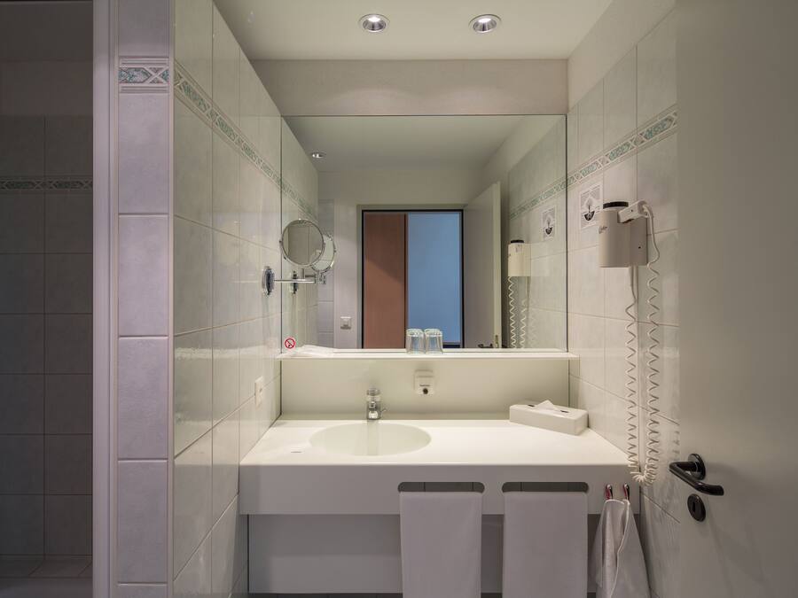 Un bagno moderno con lavandino, specchio e portasciugamani.