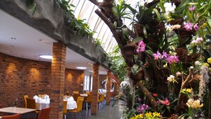 Un restaurant aux murs de briques, aux chaises orange et aux tables dressées pour le service.