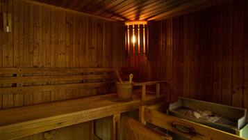 Eine Holzzimmer-Sauna mit Bänken und einem Holzwascheimer.