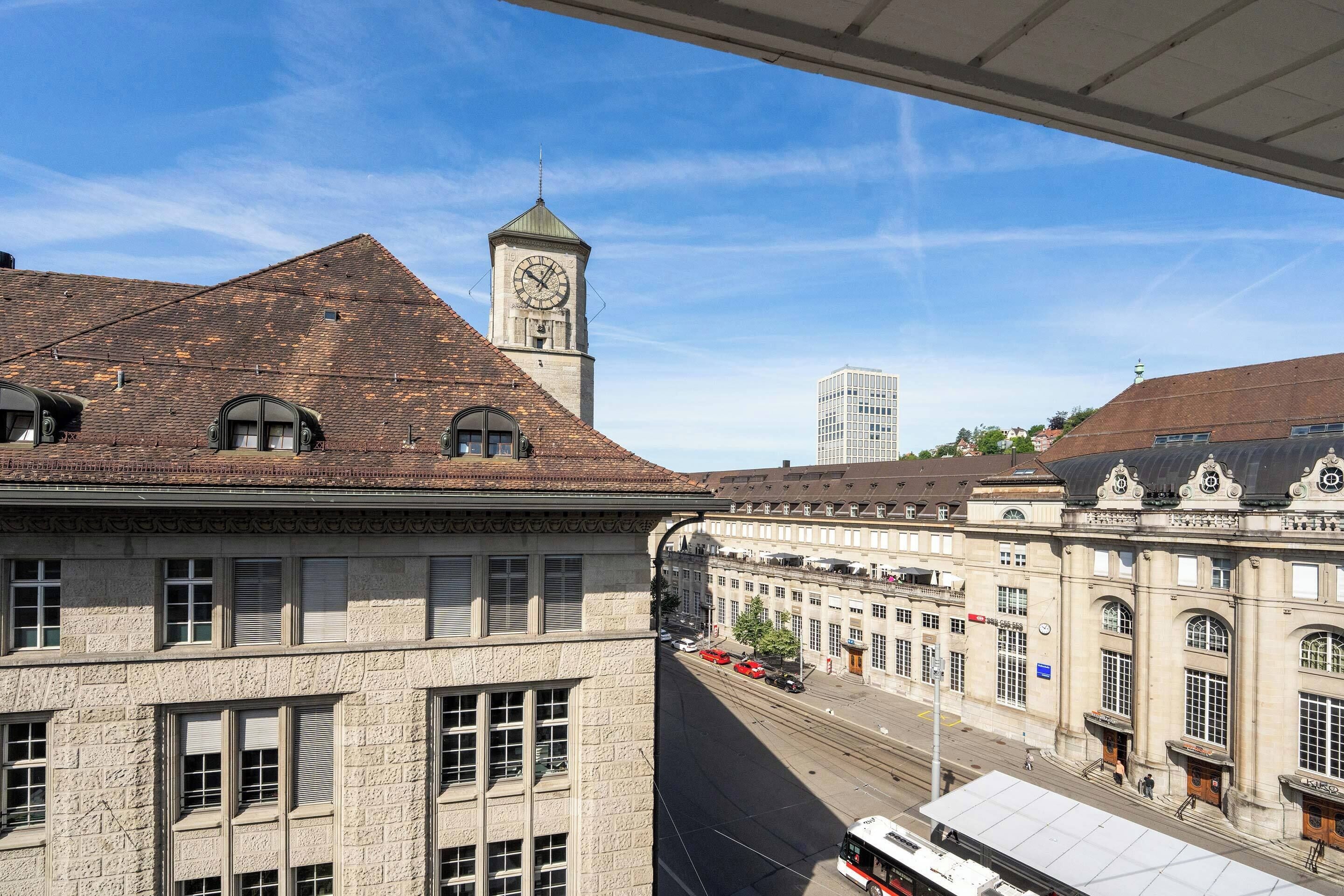 A historic building with a clock tower, large windows, and a street view.