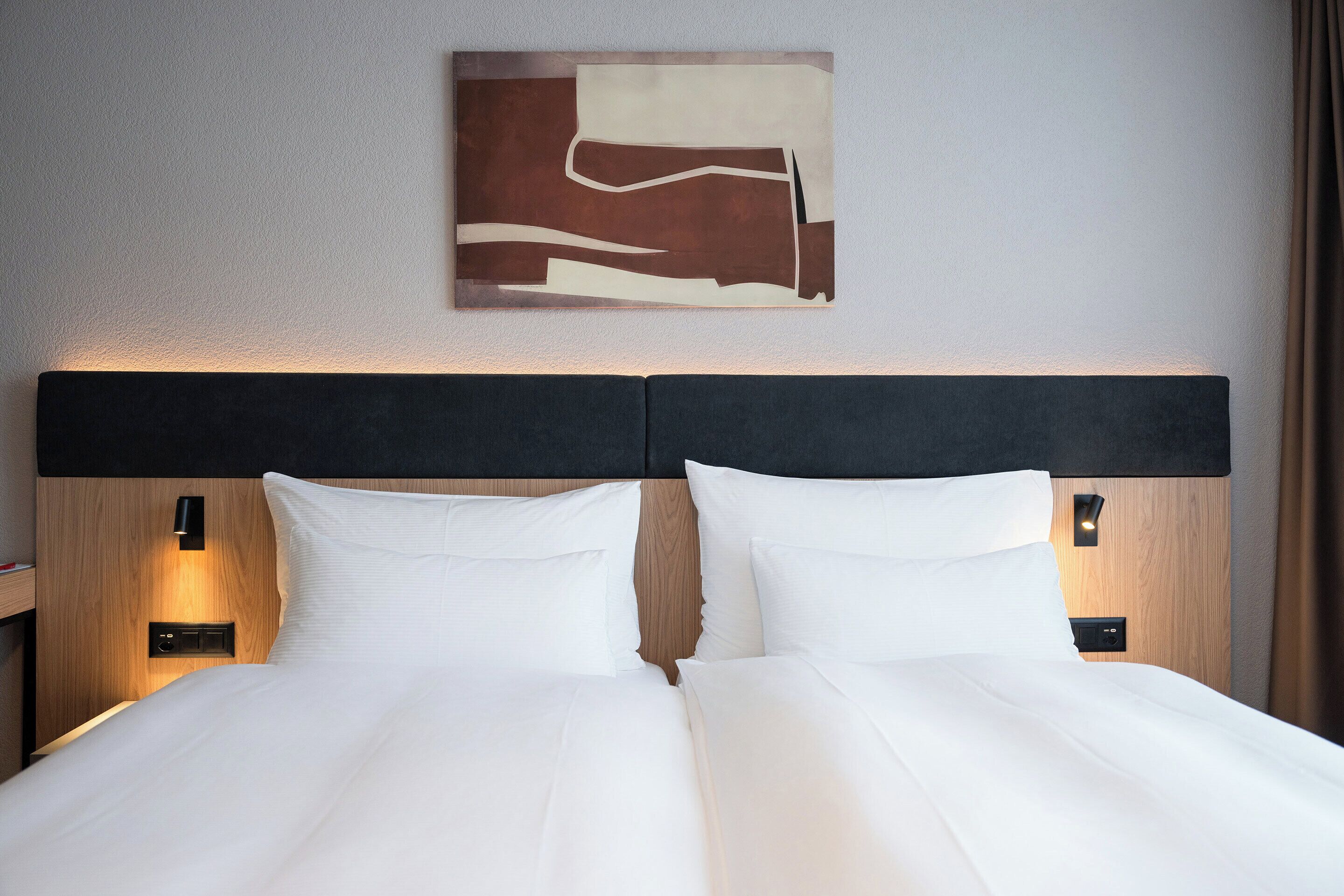 Ein Hotelzimmer mit einem Bett, zwei Nachttischen und einem an der Wand hängenden Kunstwerk.