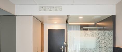 A modern hotel room with a bed, a shower area, a toilet, and a wardrobe.