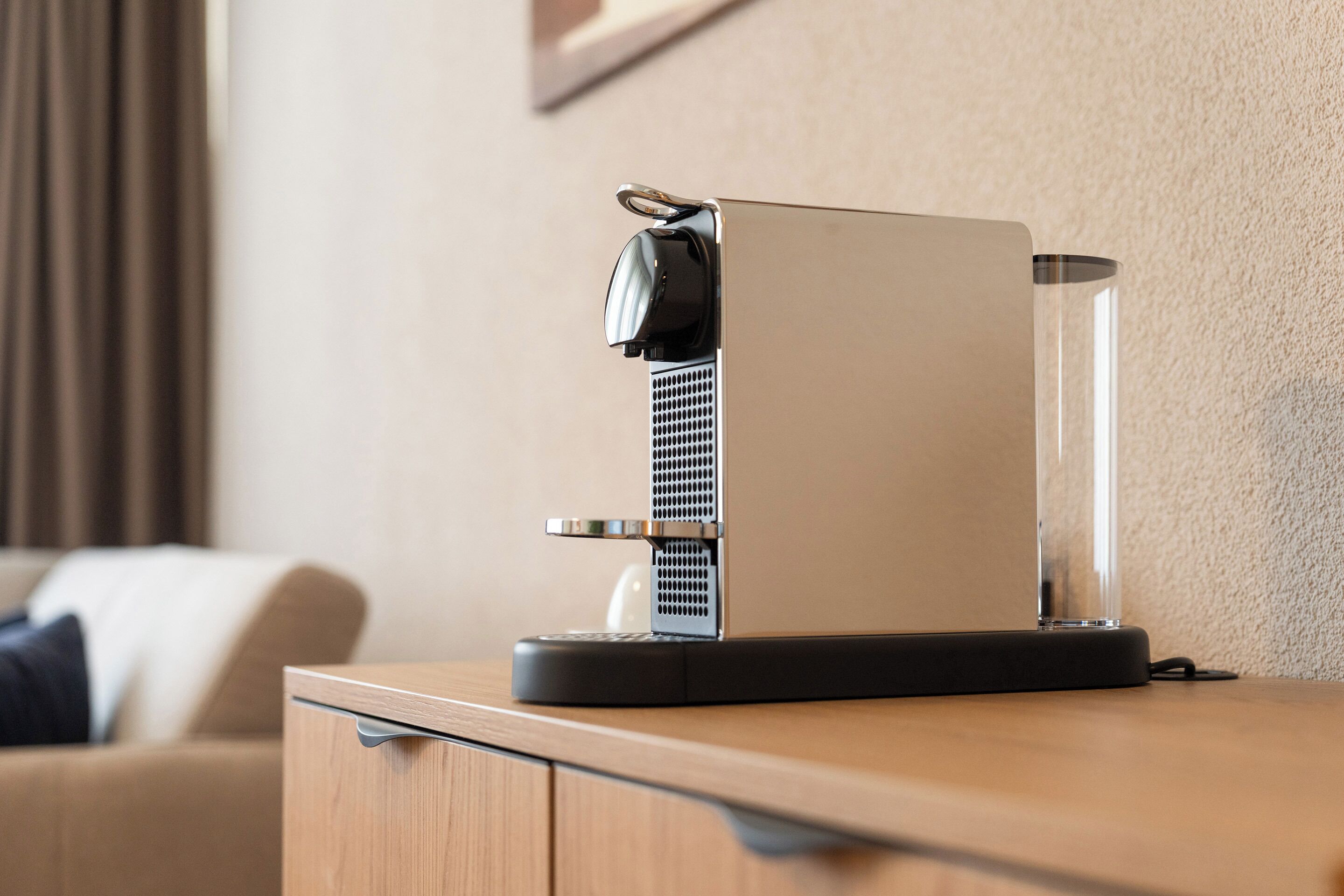 Una cafetera moderna sobre una encimera de madera en una habitación de hotel.