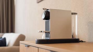 Una cafetera moderna sobre una encimera de madera en una habitación de hotel.