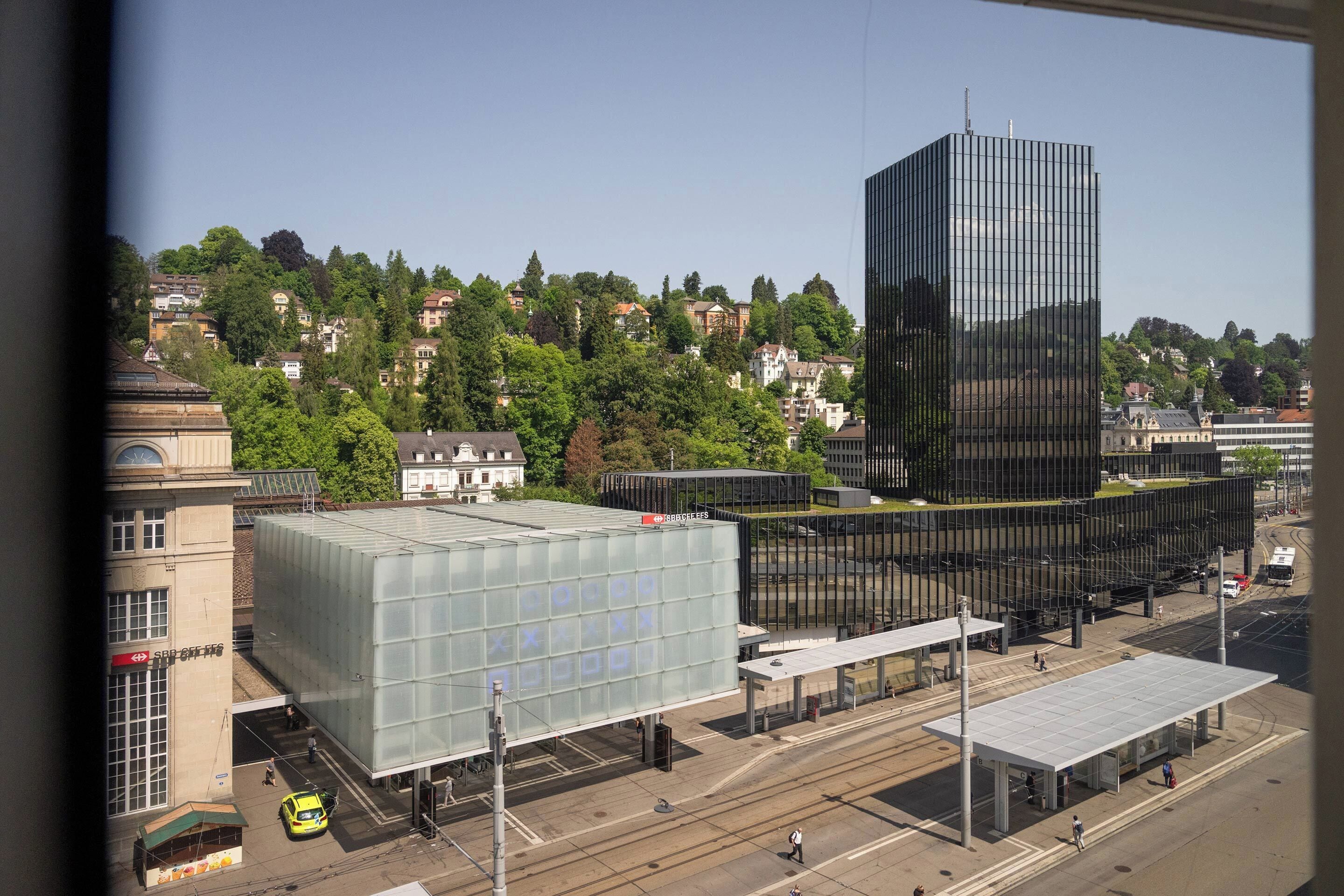 A modern building with a glass facade, surrounded by a mix of residential and commercial structures.