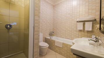 A modern bathroom with a glass-enclosed shower, a white toilet, a bathtub, and a sink with a mirror.