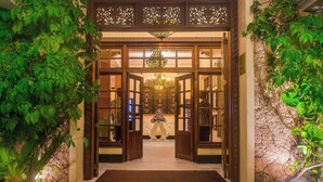 L’entrée d’un hôtel, avec une façade en bois, un lustre et une composition florale.