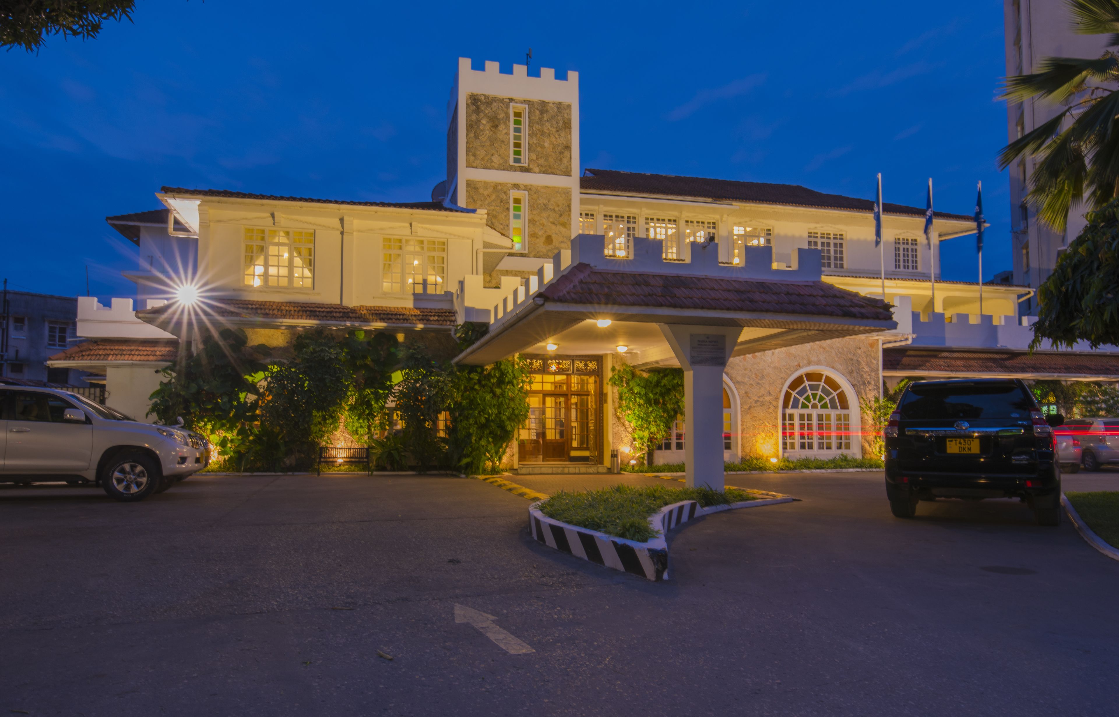 Un hôtel dont la façade ressemble à celle d’un château, avec une entrée couverte et un espace de stationnement.