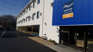 Edificio de Hampton Village Inn con toldo azul, estacionamiento y cielo despejado.