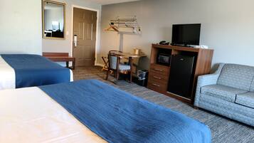 A hotel room with two beds, a desk, a television, and a sofa.