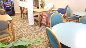 A dining area with tables and chairs, a refrigerator, and a Pepsi vending machine. - Hampton Village Inn (Hampton)