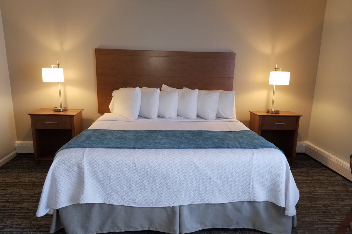 A hotel room with a large bed, two bedside tables, and a headboard.