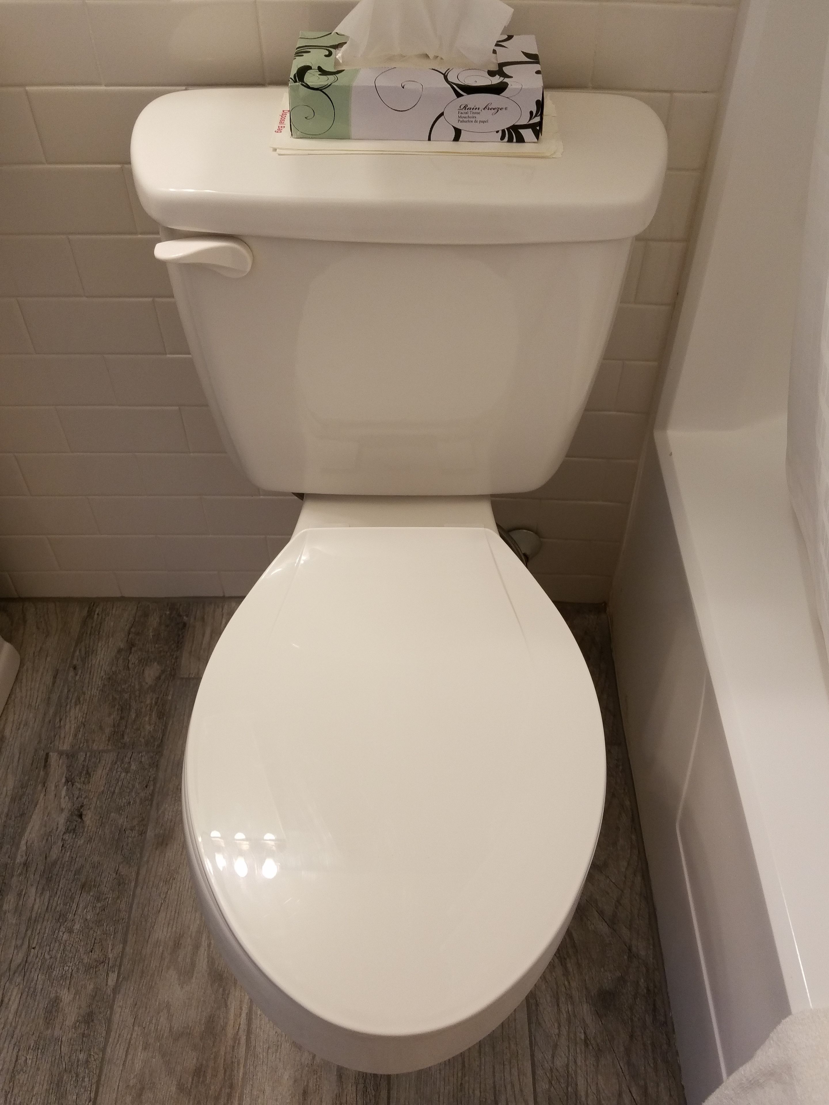 Des toilettes blanches avec un présentoir à mouchoirs sur le dessus.