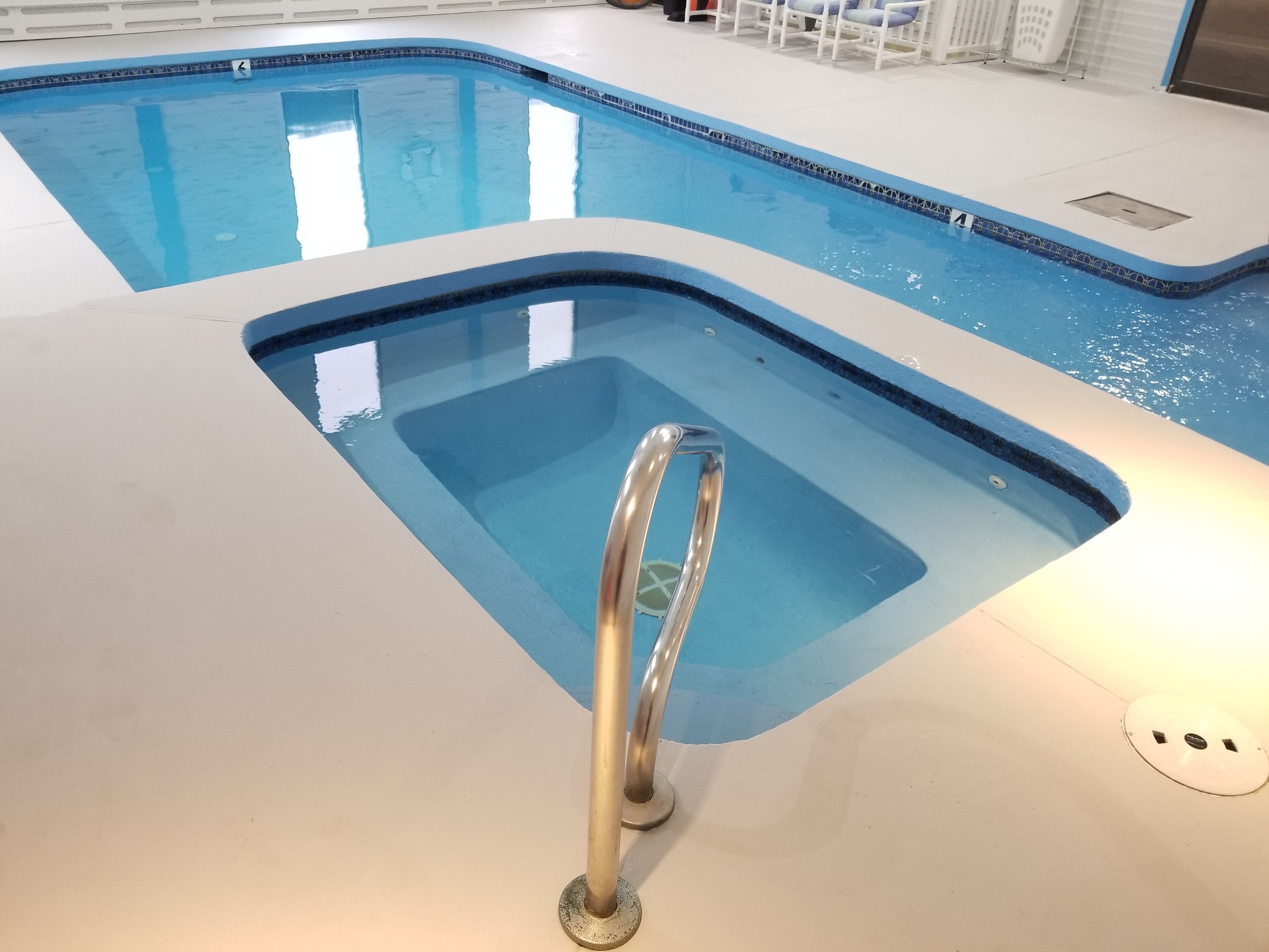 Une piscine intérieure dotée d’une zone à eau claire et d’une rambarde métallique.