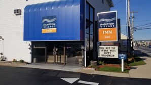 A Hampton Village Inn building with a blue awning and signage indicating amenities like a pool hot tub, sauna, and Wi-Fi. - Hampton Village Inn (Hampton)