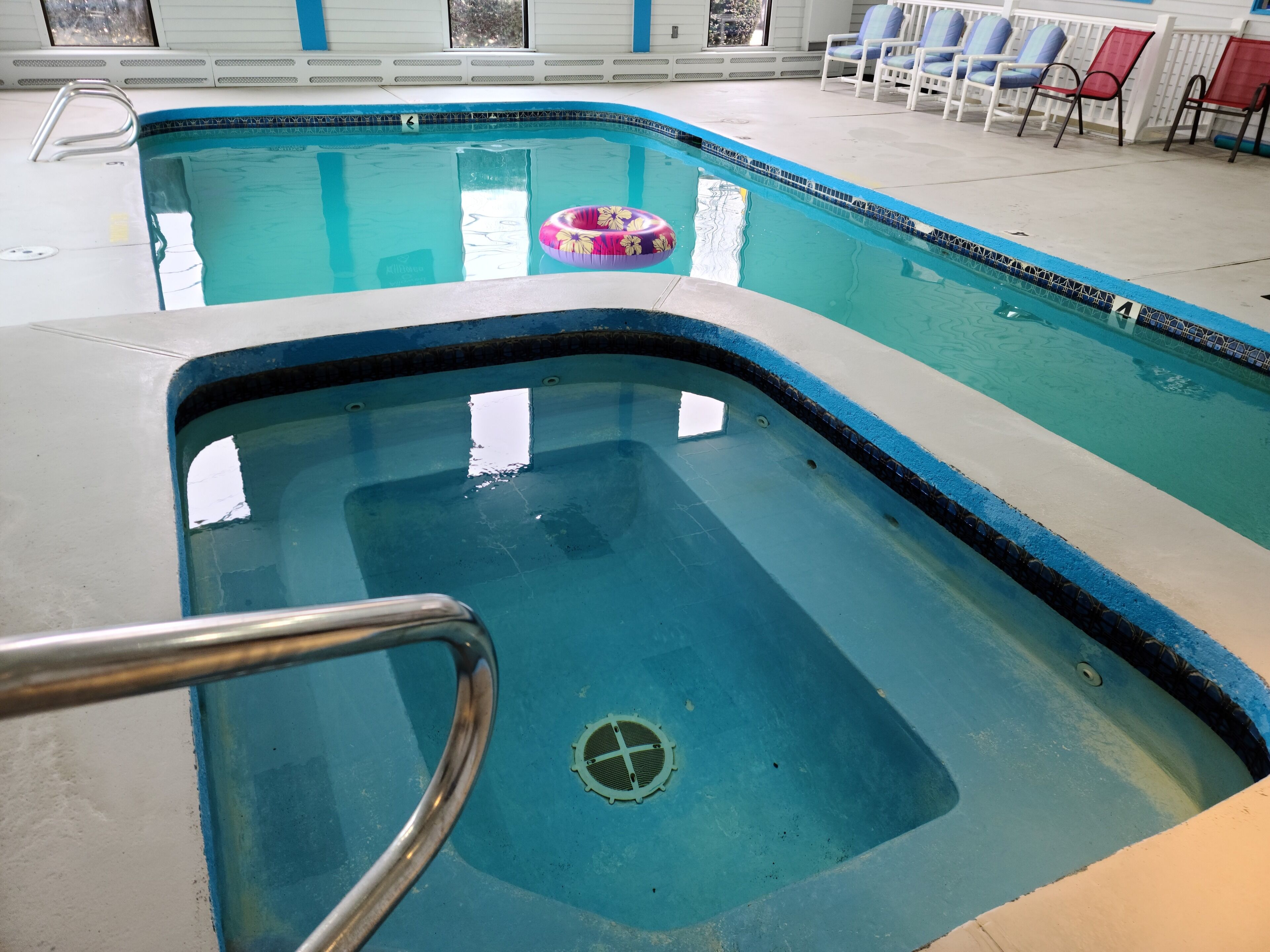 An indoor swimming pool with a diving board, lounge chairs, and a poolside area.