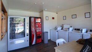 Eine kleine Küche mit Automaten, einer Mikrowelle und einer Waschmaschine.