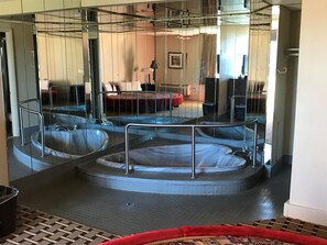 A spa area with three hot tubs, a red chair, and a mirror reflecting the room.