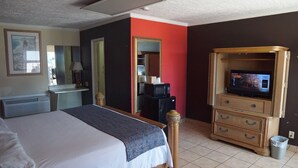 A hotel room with a bed, a desk, a television, and a mirror. - La Hacienda Hotel (Laredo)