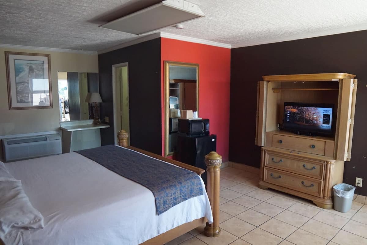 A hotel room with a bed, a desk, a television, and a mirror.