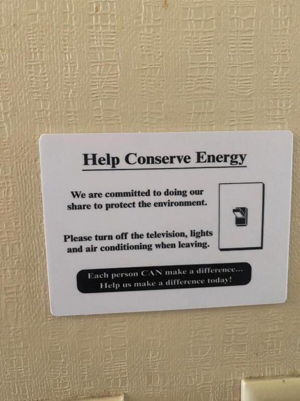 A sign on a wall that reads 'Help Conserve Energy' with instructions to turn off lights and air conditioning.
