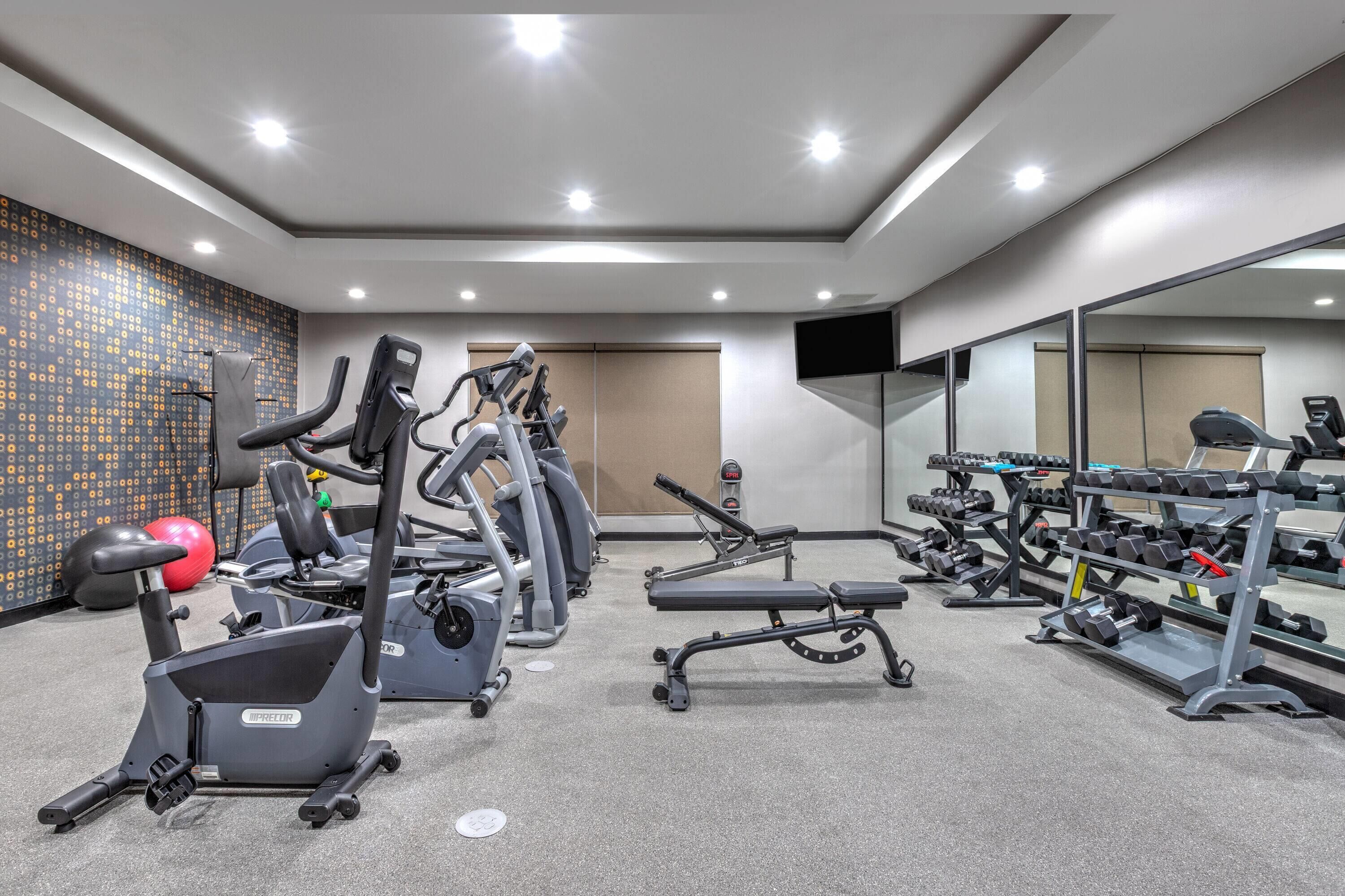 A gym with treadmills, elliptical machines, and weight benches.