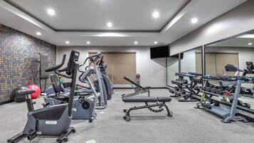 A gym with treadmills, elliptical machines, and weight benches.