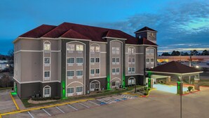 A multi-story hotel with a red roof, a covered entrance, and a parking lot. - La Quinta Inn & Suites by Wyndham Paris (Paris)