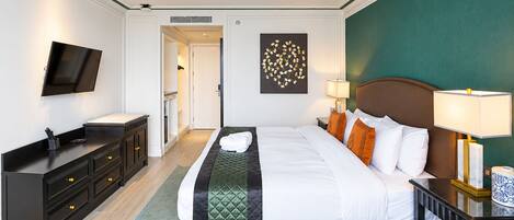 Una habitación de hotel con cama, mesitas de noche, televisor, escritorio y armario.