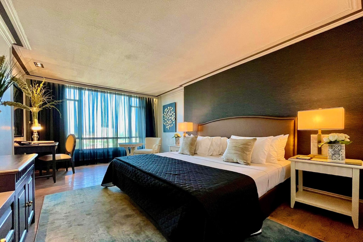 Une chambre d’hôtel avec un grand lit, des tables de chevet, un bureau et une chaise.