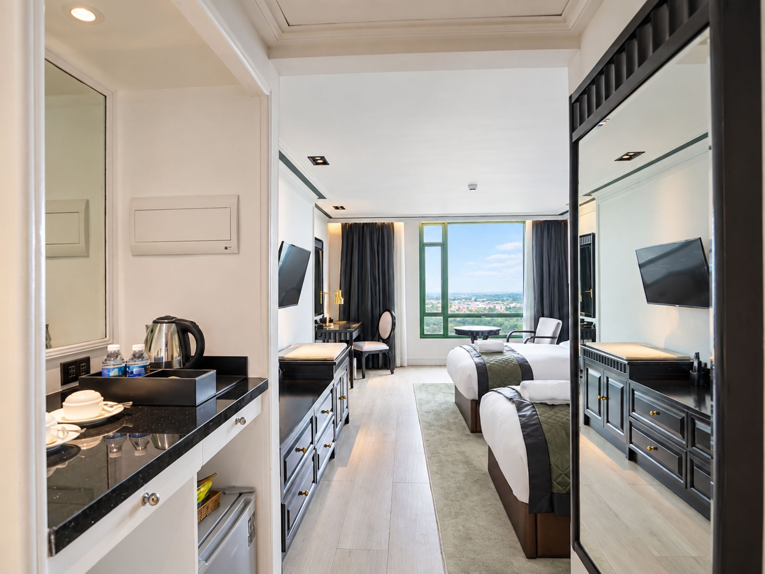 Habitación de hotel con cama, escritorio, silla, televisión y un amplio ventanal con vistas.