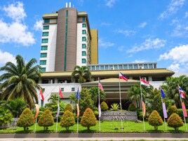 Un hotel con una entrada destacada, varias banderas y un jardín bien cuidado.