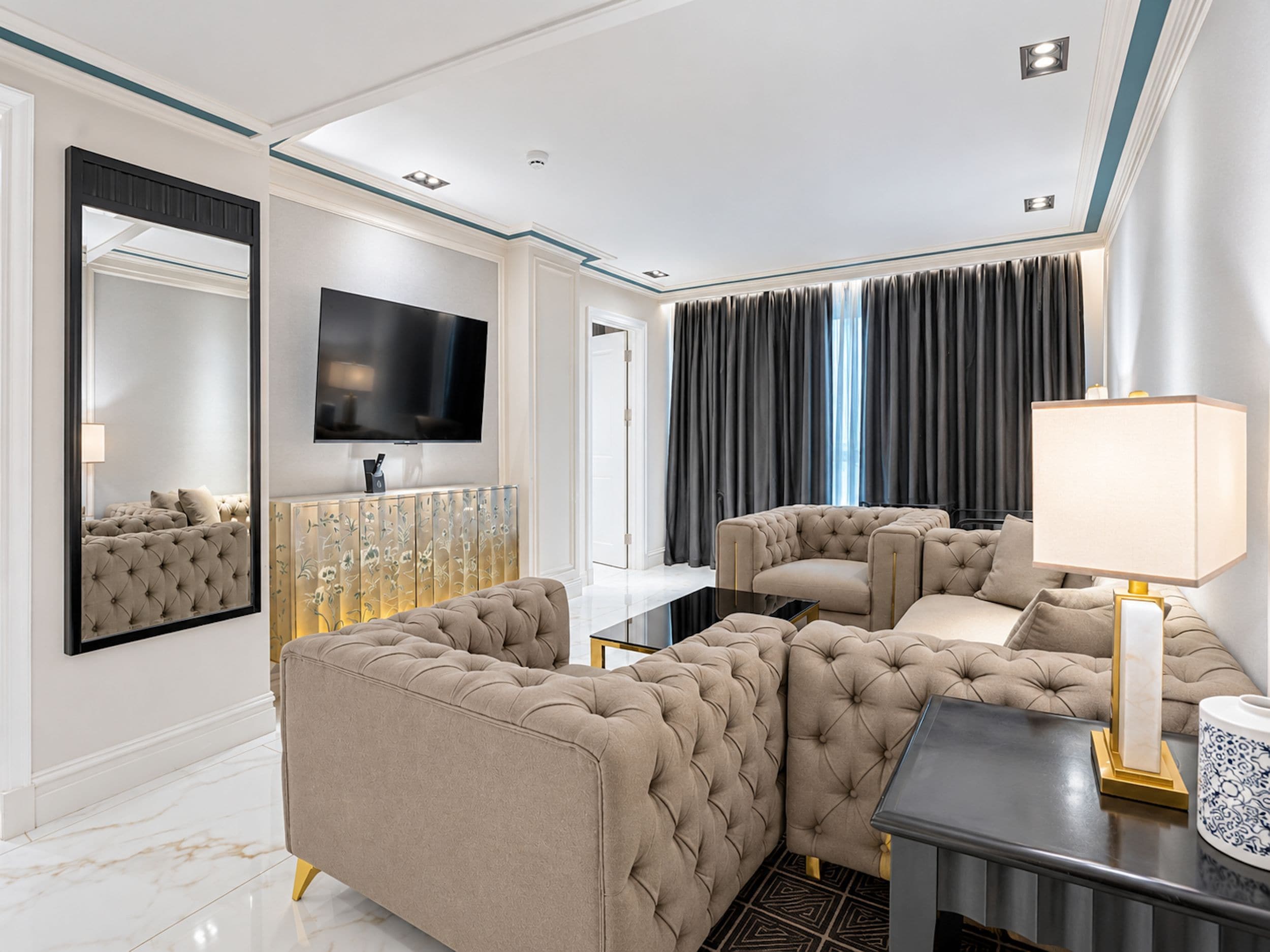 A modern living room with a large flat-screen TV, a sofa set, a coffee table, and a lamp.