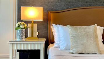 A hotel room with a bed, a bedside table with a lamp, and a decorative vase.