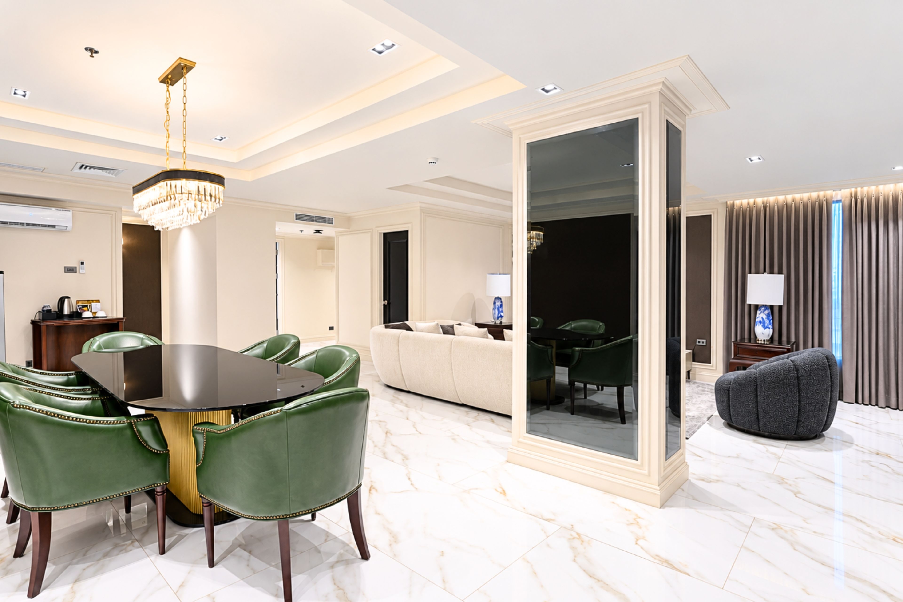 A modern dining area with a marble floor, green upholstered chairs, and a central table.