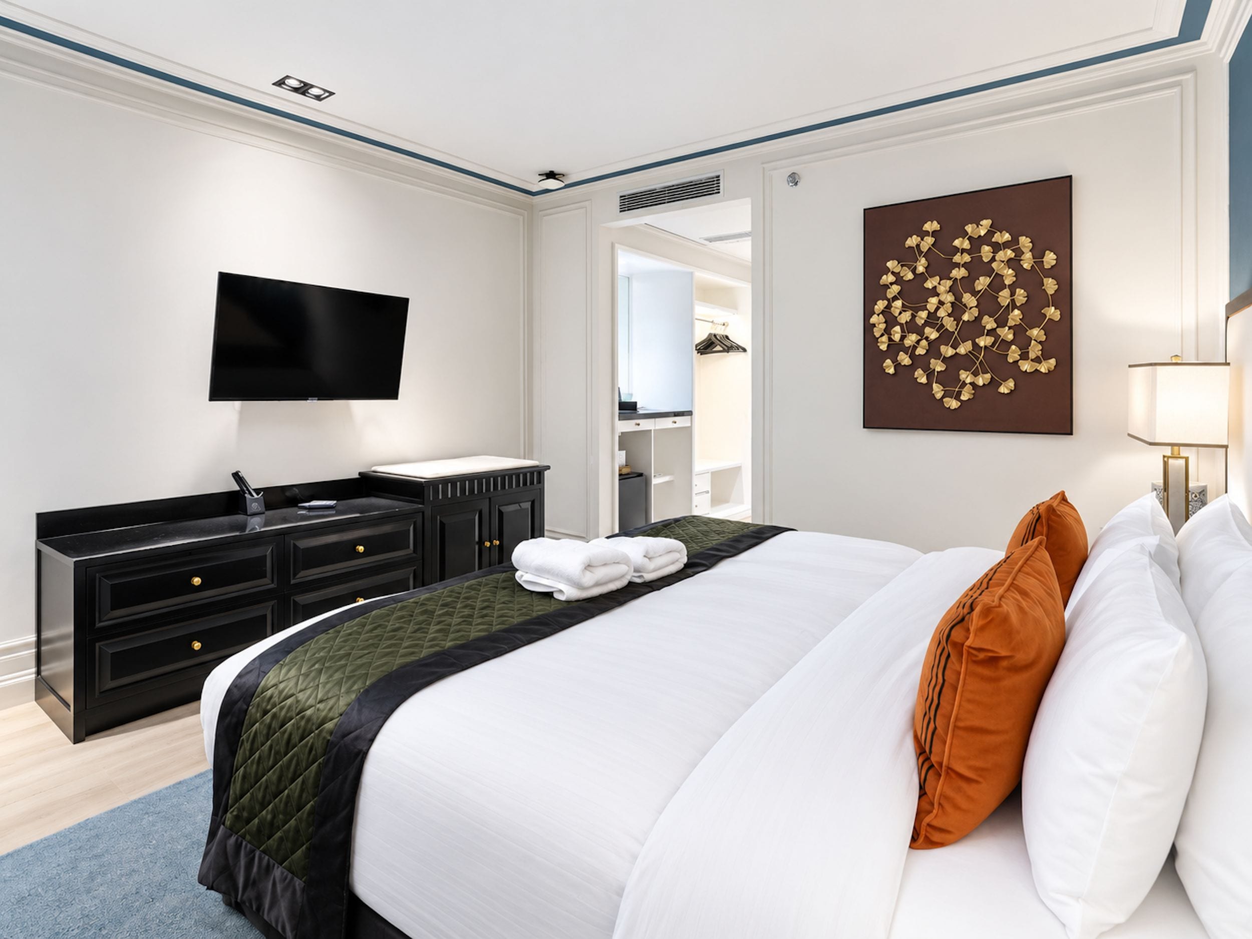 A hotel room with a bed, a flat-screen TV, a dresser, and a mirror.