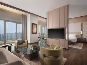 A modern hotel room with a large TV, comfortable seating, a desk, and a balcony with a city view. - The Ritz-Carlton Jakarta, Pacific Place (Jakarta)