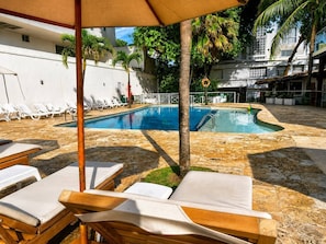 A swimming pool with lounge chairs and a palm tree. - Hotel Playa Club (Cartagena)