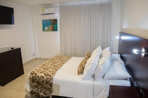 A hotel room with a bed, a dresser, a TV mounted on the wall, and an air conditioning unit. - Hotel Playa Club (Cartagena)