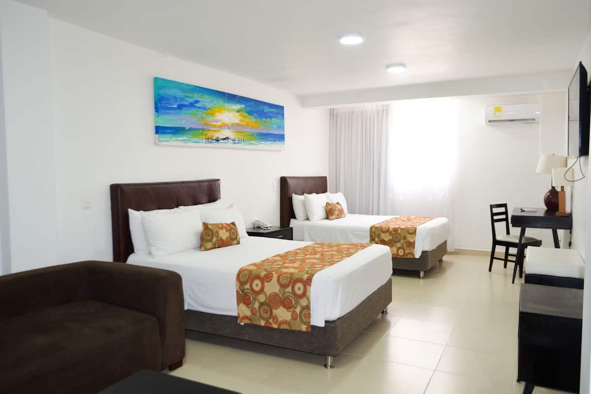 A hotel room with two beds, a desk, and a chair.