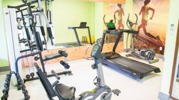 A gym with exercise equipment including a treadmill, elliptical, and weight machines.