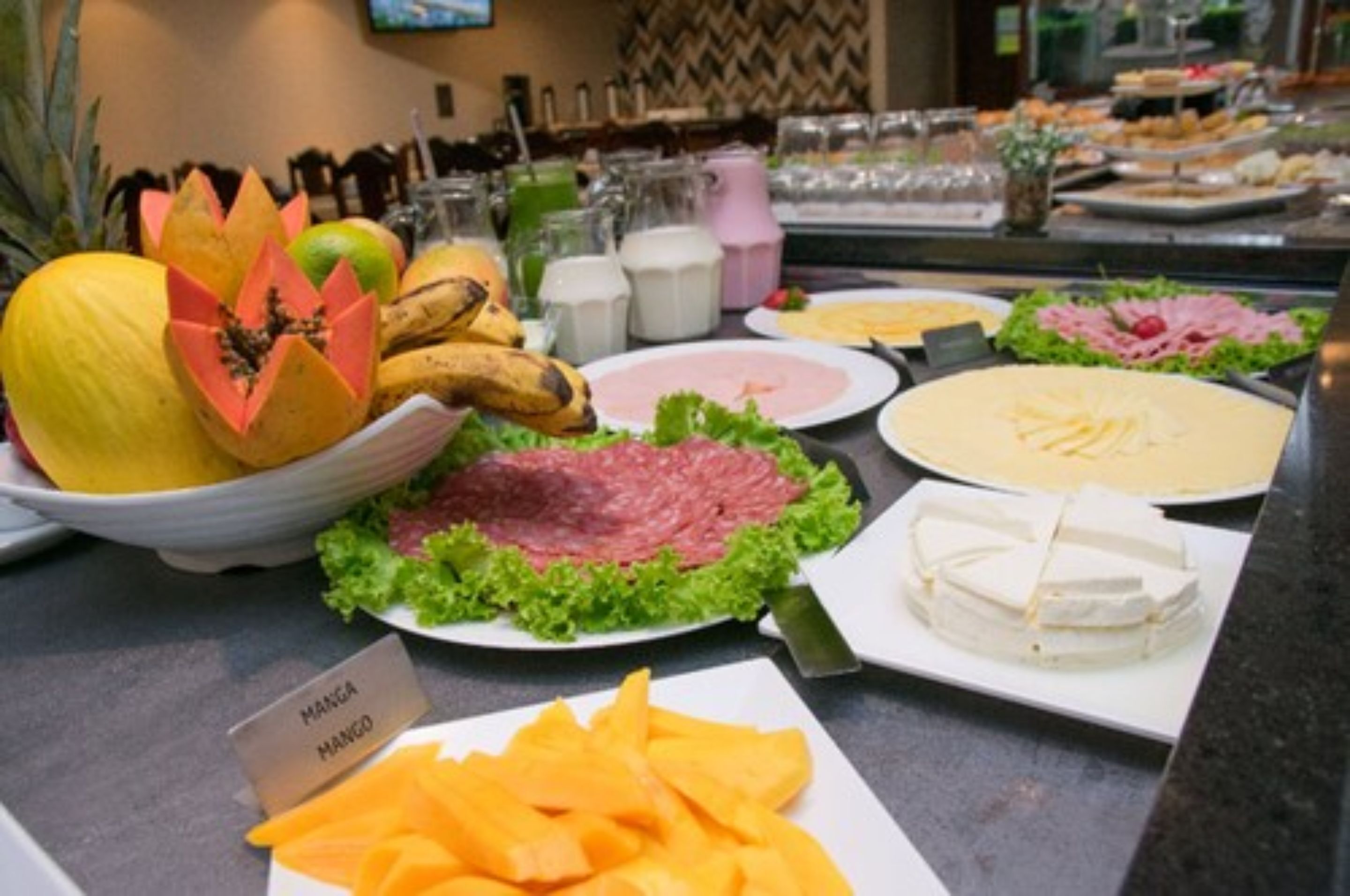 A buffet with various food items including mango, cheese, and meat.