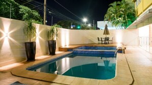A swimming pool with a tiled edge, surrounded by a low wall and potted plants. - Hotel Vale Verde (Campo Grande)