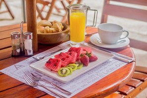 A breakfast setting with a plate of fruit, a glass of orange juice, and a cup on a wooden table. - Leblón Suites Hotel Milla de Oro (Medellín)