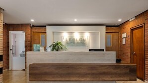 A reception desk with a sign reading "LEBLON SUITES HOTEL" in a modern lobby with brick walls and wooden accents. - Leblón Suites Hotel Milla de Oro (Medellín)
