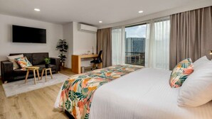 A modern hotel room with a large bed, a desk, a sofa, and a TV. - Leblón Suites Hotel Milla de Oro (Medellín)