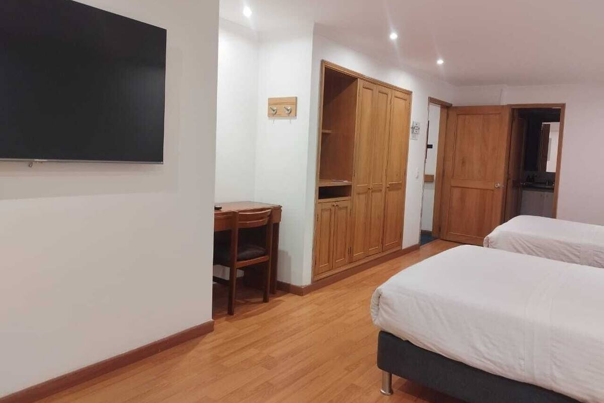 Un dormitorio con dos camas, un escritorio y un armario.