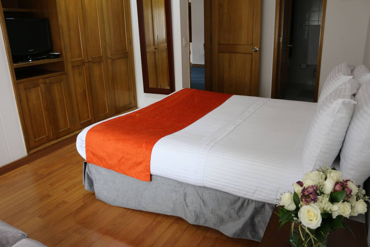 Una habitación de hotel con cama, armario de madera y televisor.